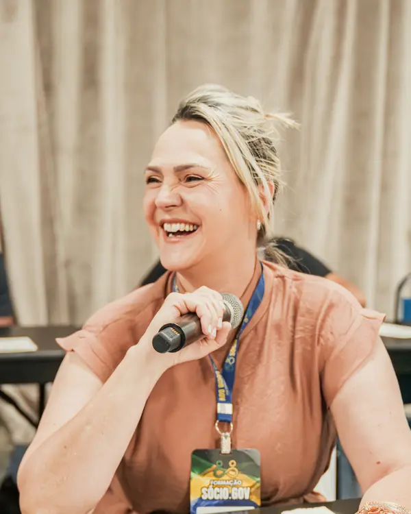 Participante sorrindo com a apostila e o microfone